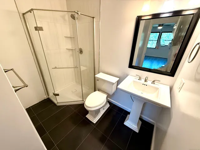 a bathroom with a sink a toilet a mirror and shower