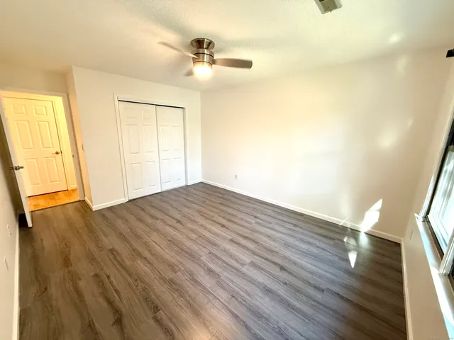a view of empty room with wooden floor and fan