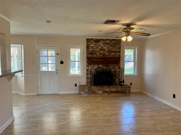 a view of a livingroom with a fireplace a chandelier and windows