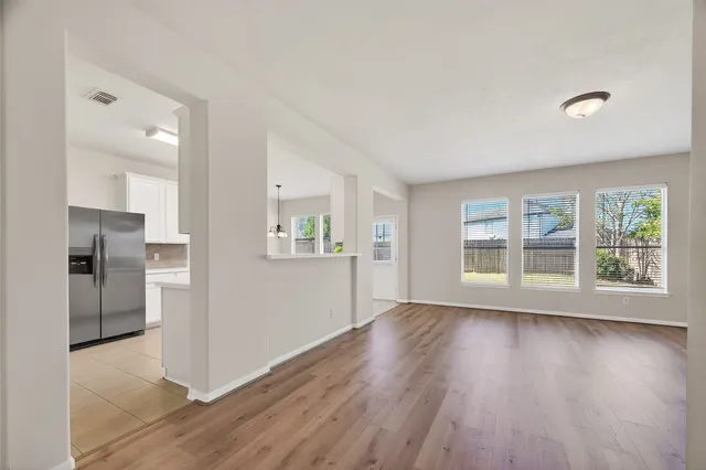 a view of an empty room with a window and wooden floor