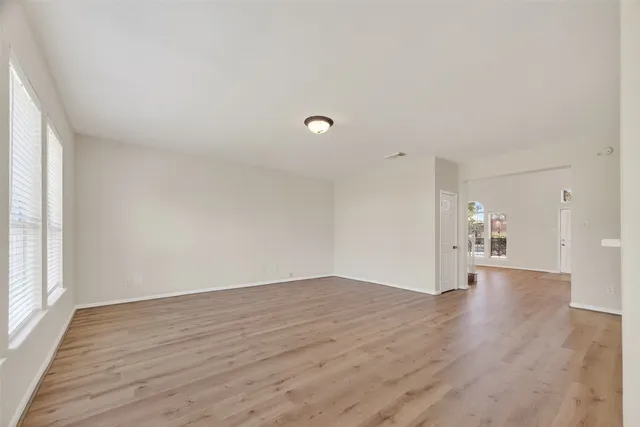 a view of an empty room with wooden floor and a window