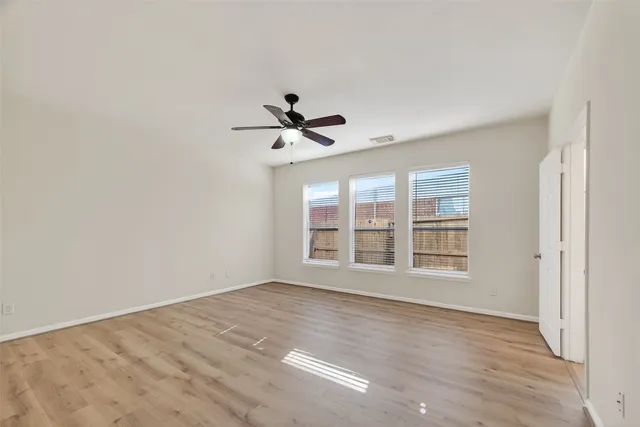 a view of an empty room with a window and wooden floor
