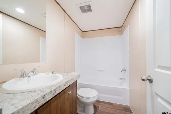 a bathroom with a granite countertop sink a toilet and shower