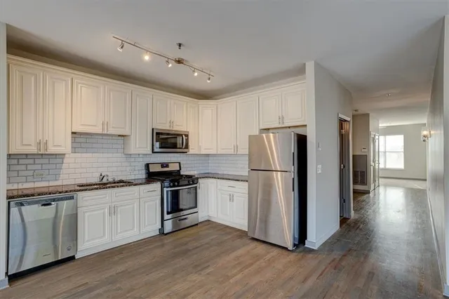 a kitchen with cabinets stainless steel appliances and wooden floor