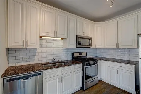 a kitchen with granite countertop white cabinets and stainless steel appliances