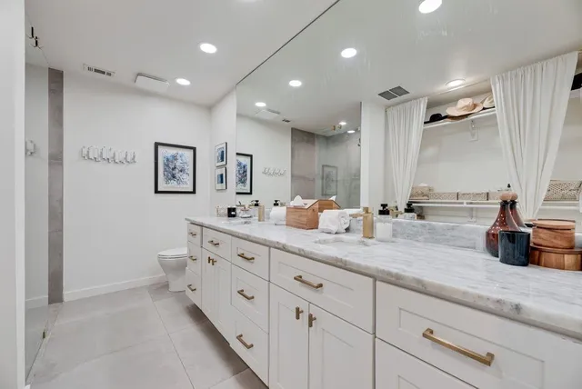 a spacious bathroom with double sink a mirror and a shower