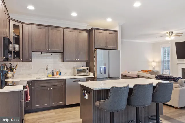 a kitchen with stainless steel appliances granite countertop a sink a stove a refrigerator cabinets and chairs