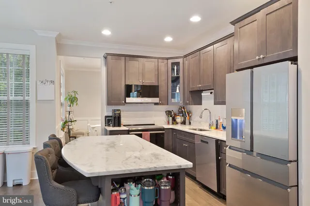 a kitchen with stainless steel appliances a refrigerator a sink a stove a table and chairs