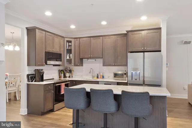 a kitchen with stainless steel appliances granite countertop a sink a stove a refrigerator cabinets and chairs