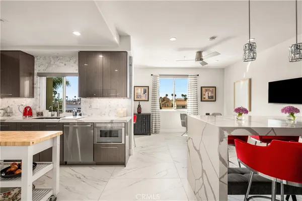 a kitchen with stainless steel appliances a stove a sink dishwasher a microwave oven with white cabinets and chairs