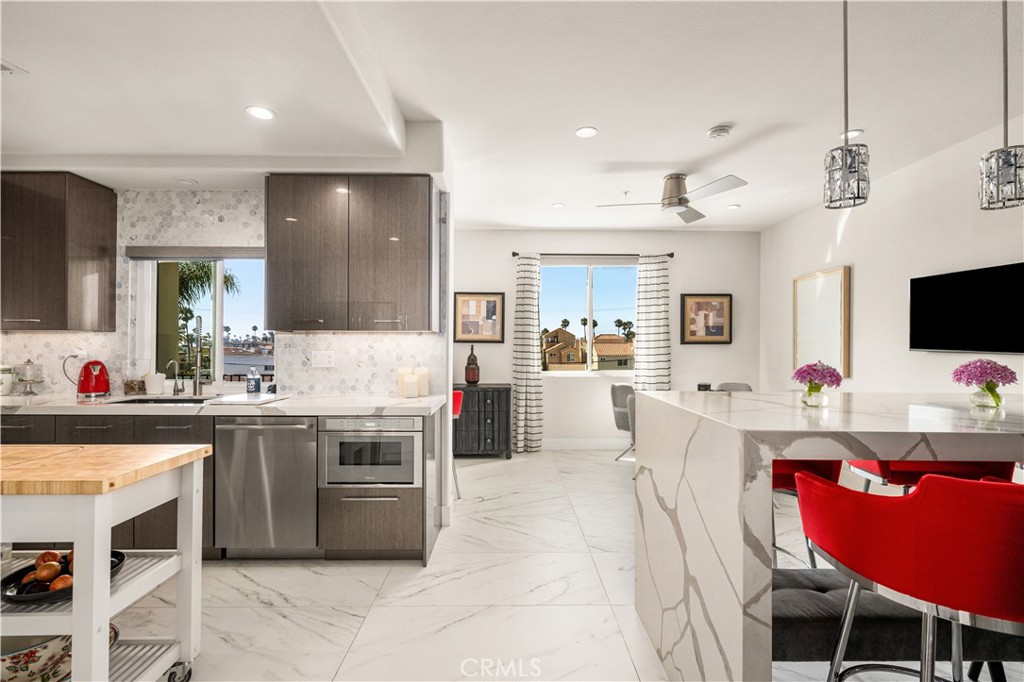 340 5th Street Huntington Beach, CA 92648 - Photo 7 of 48 a kitchen with stainless steel appliances a stove a sink dishwasher a microwave oven with white cabinets and chairs