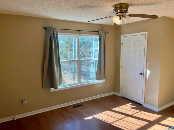 a view of an empty room with a window and wooden floor