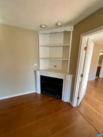 a view of empty room with wooden floor and fireplace