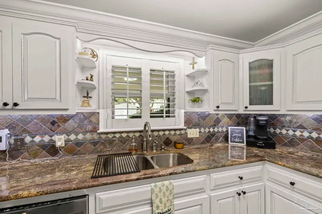 a kitchen with stainless steel appliances a sink a stove and white cabinets