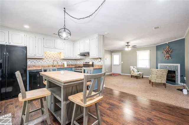 a kitchen with stainless steel appliances a dining table chairs refrigerator and sink