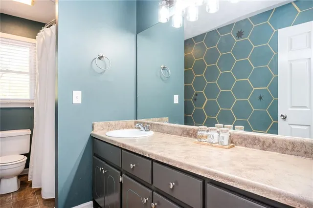 a bathroom with a granite countertop sink a mirror and a toilet