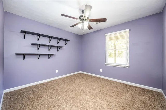 an empty room with a chandelier fan and windows