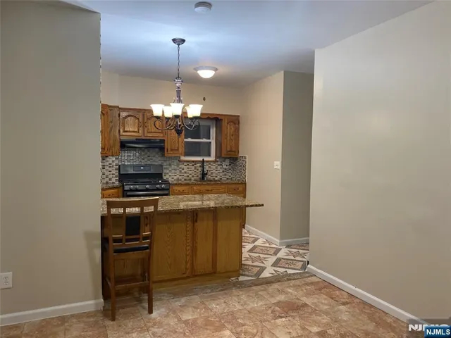 a room with kitchen island a chandelier stainless steel appliances and cabinets