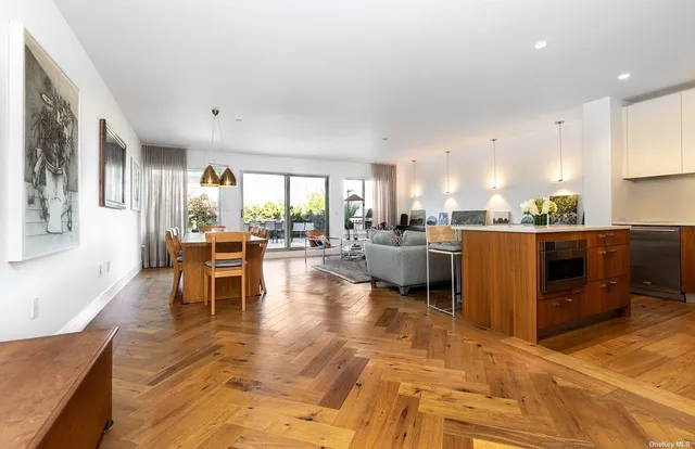 a living room with couches chairs and kitchen view with wooden floor