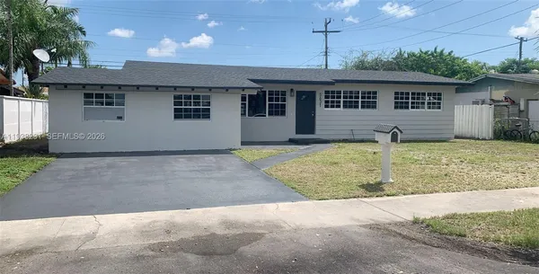 a front view of a house with a yard and potted plants