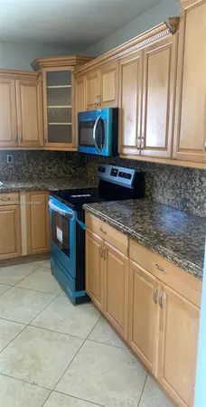a kitchen with granite countertop a sink a stove and cabinets