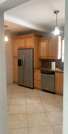 a kitchen with stainless steel appliances granite countertop a refrigerator a sink and a stove