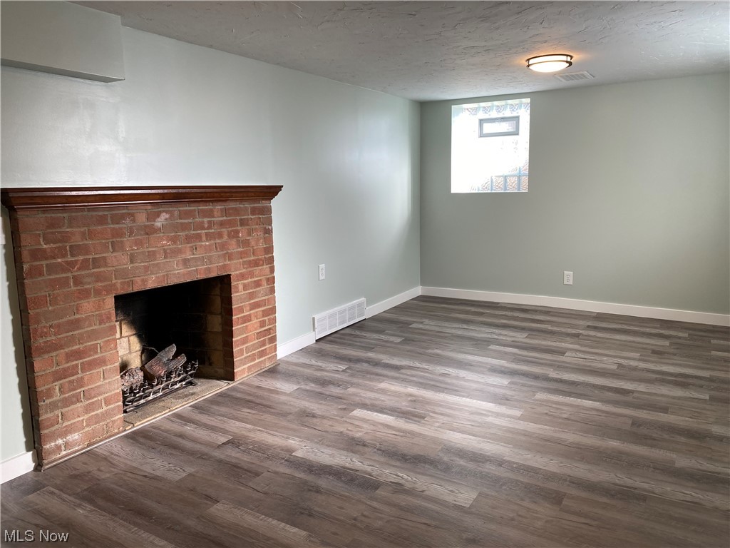 1147 Richmond Road Cleveland, OH 44124 - Photo 25 of 28 Unfurnished living room featuring dark hardwood / wood-style floors, a brick fireplace, and a textured ceiling