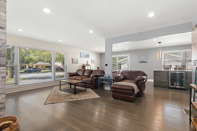 a living room with furniture large window and wooden floor