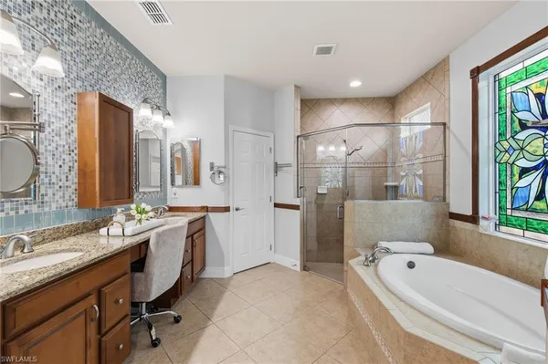 a bathroom with a granite countertop tub sink a mirror a bathtub and shower