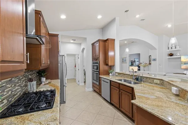 a large kitchen with stainless steel appliances granite countertop a sink stove and refrigerator