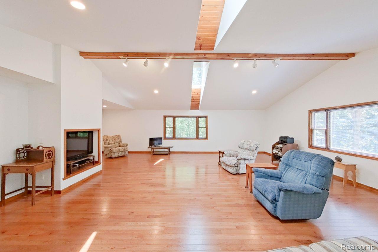 10201 Washburn Road Goodrich, MI 48438 - Photo 23 of 85 Spacious living area featuring high vaulted ceilings with exposed wood beams, skylights, wood-finish flooring, recessed lighting, and multiple windows with wood trim