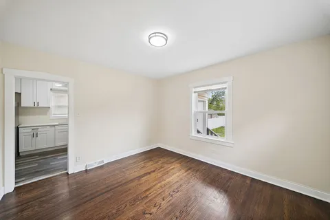 a view of an empty room with a window and wooden floor