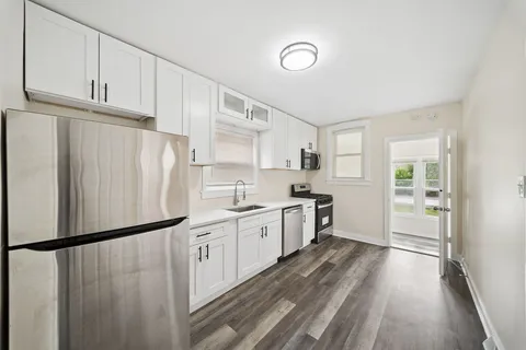 a kitchen with white cabinets and refrigerator