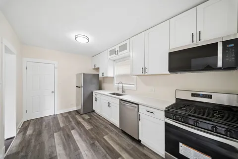 a kitchen with stainless steel appliances a sink dishwasher a stove and white cabinets