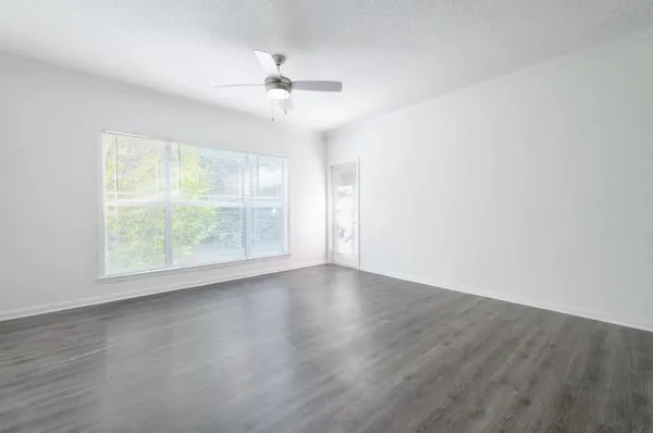 an empty room with wooden floor chandelier fan and windows