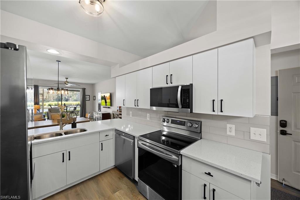 a kitchen with a sink a stove a refrigerator and white cabinets
