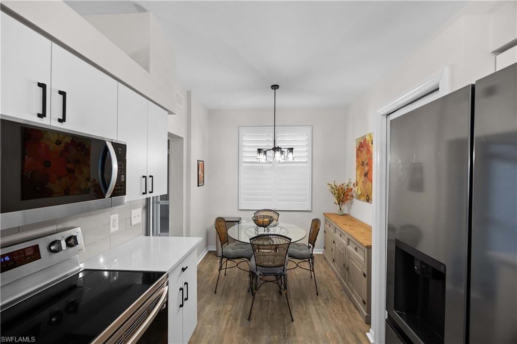 3760 Sawgrass Way, Unit 3514 Naples, FL 34112 - Photo 12 of 43 a kitchen with stainless steel appliances a stove a sink dishwasher a refrigerator white cabinets and wooden floor