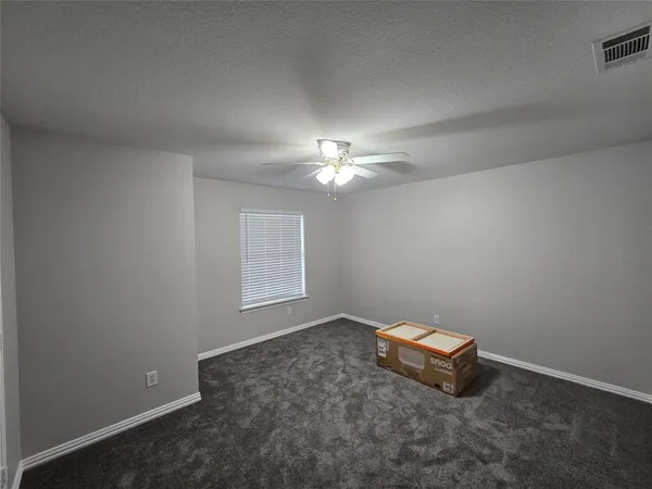 an empty room with windows and chandelier fan