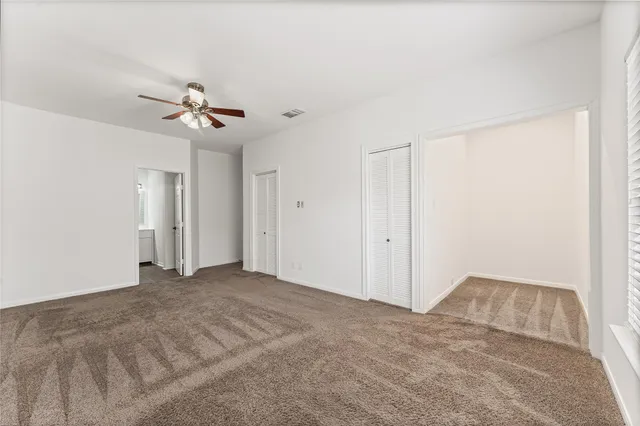 an empty room with a chandelier fan and windows