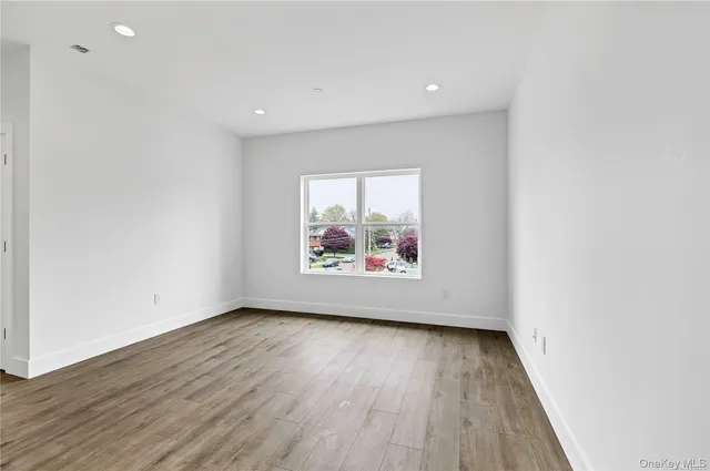a view of an empty room with wooden floor and window
