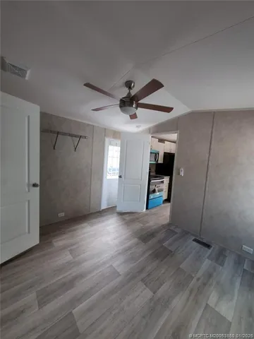 an empty room with wooden floor and a ceiling fan
