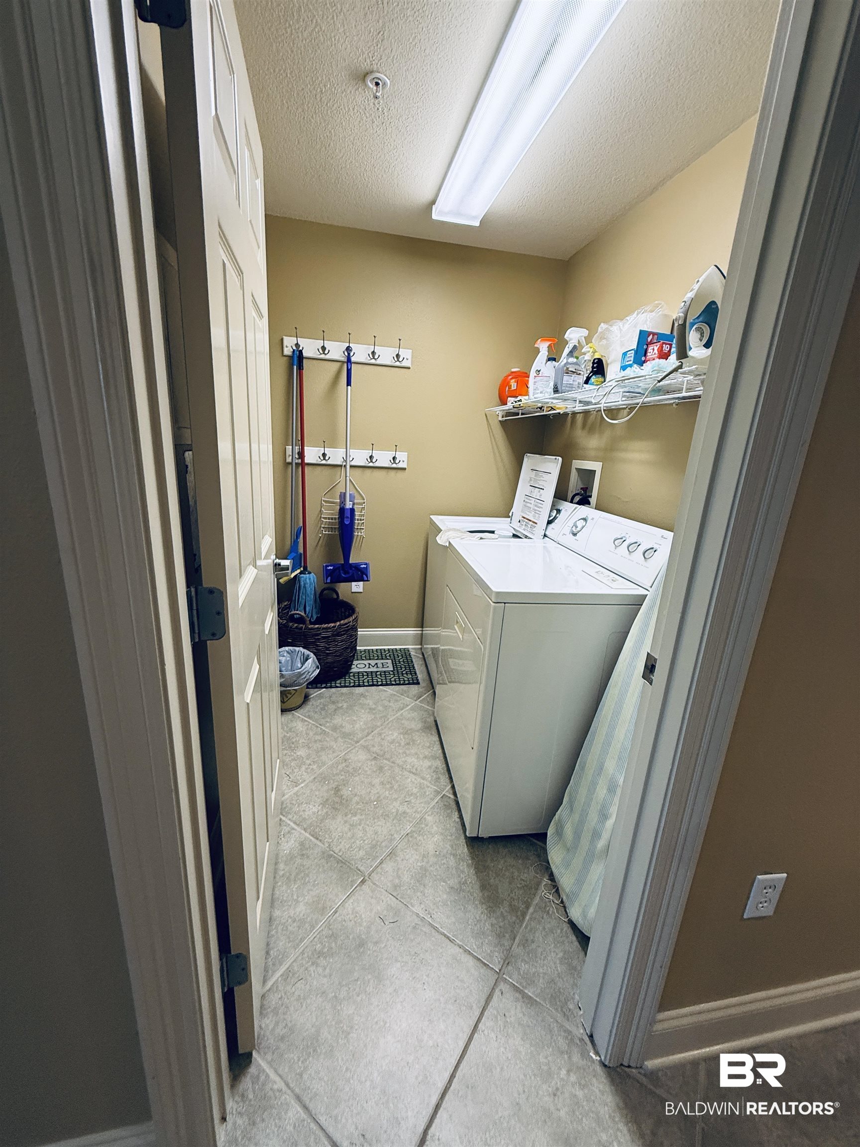 27800 Canal Road, Unit 409 Orange Beach, AL 36561 - Photo 12 of 22 Laundry room with washing machine and clothes dryer, a textured ceiling, and light tile patterned floors