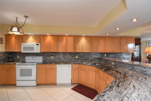a large kitchen with stainless steel appliances kitchen island granite countertop a sink and cabinets