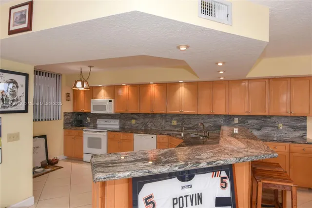 a kitchen with stainless steel appliances granite countertop a sink and a refrigerator