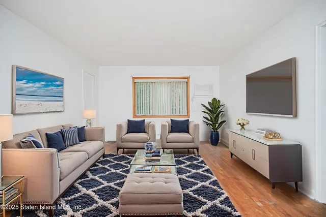 a living room with furniture a flat screen tv and a window