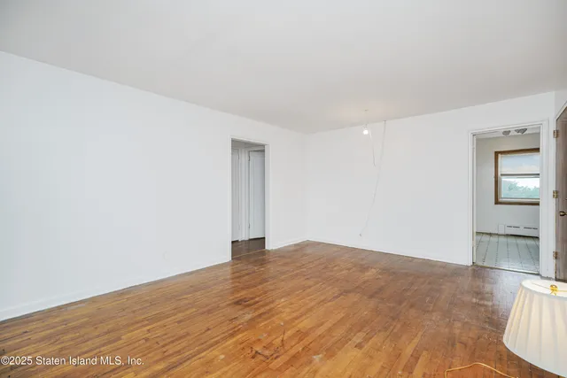 a view of an empty room with window and wooden floor