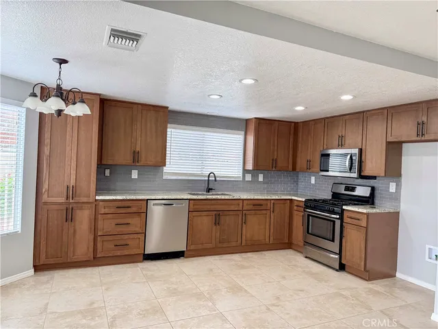 a kitchen with stainless steel appliances granite countertop a stove top oven a sink dishwasher and a refrigerator