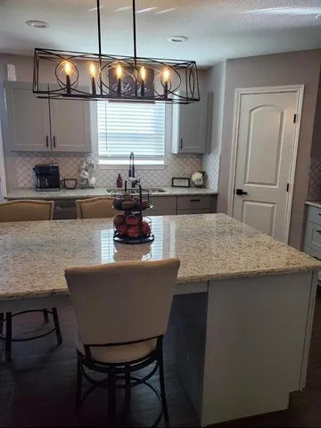 a kitchen with stainless steel appliances a table chairs in it and wooden floor