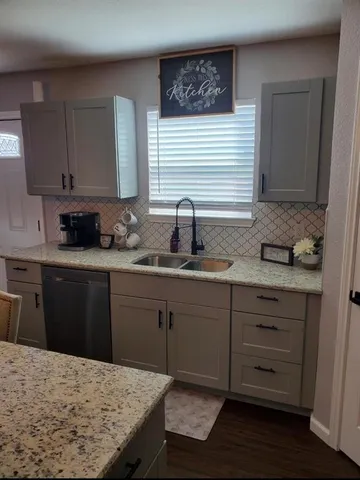 a kitchen with granite countertop a sink a counter space and cabinets