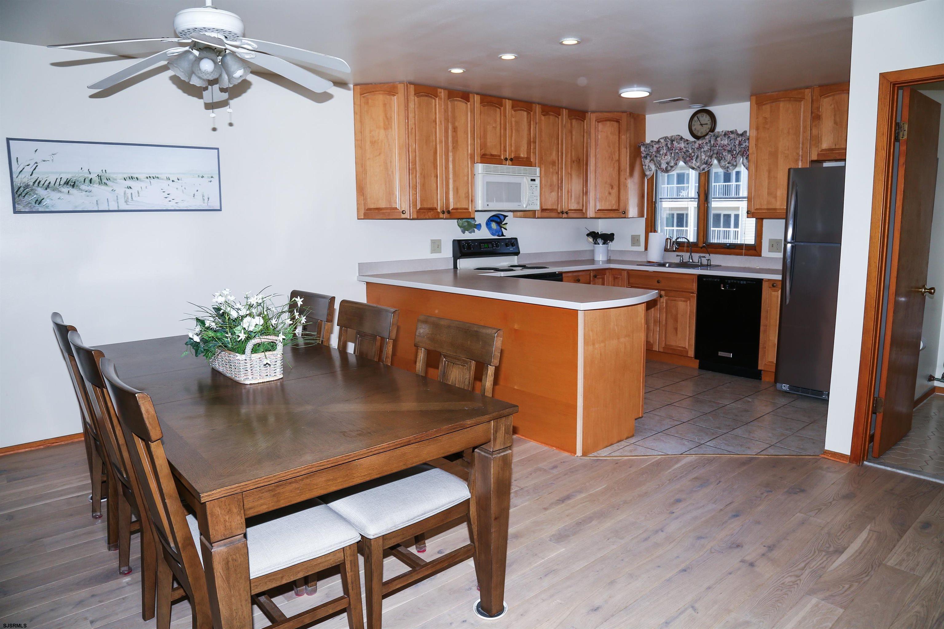 512 East Brigantine Avenue, Unit 512 Brigantine, NJ 08203 - Photo 24 of 46 a kitchen with stainless steel appliances granite countertop a stove a refrigerator a sink a dining table and chairs with wooden floor